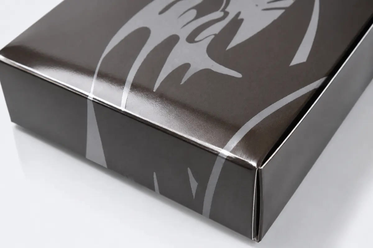 Silver paper packaging box with a high-gloss UV coating and contrasting printed pattern.